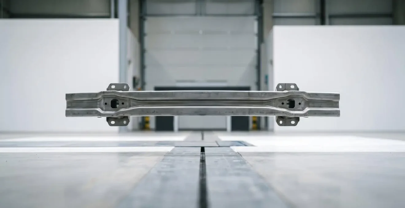 Close-up photograph showing automotive bumper reinforcement and crumple zone structural deformation patterns after a crash test.