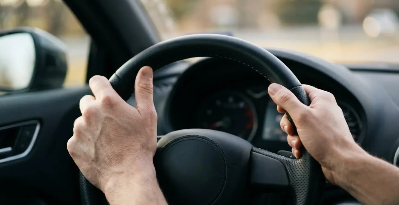 Driver hands positioned on a leather steering wheel demonstrating the proper relaxed grip technique for lane assist systems