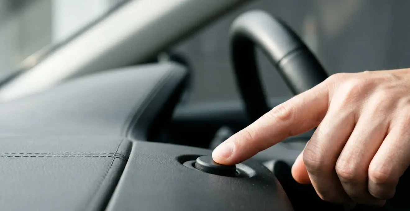 Close-up view of TPMS reset button location near vehicle steering column with finger pressing the calibration control